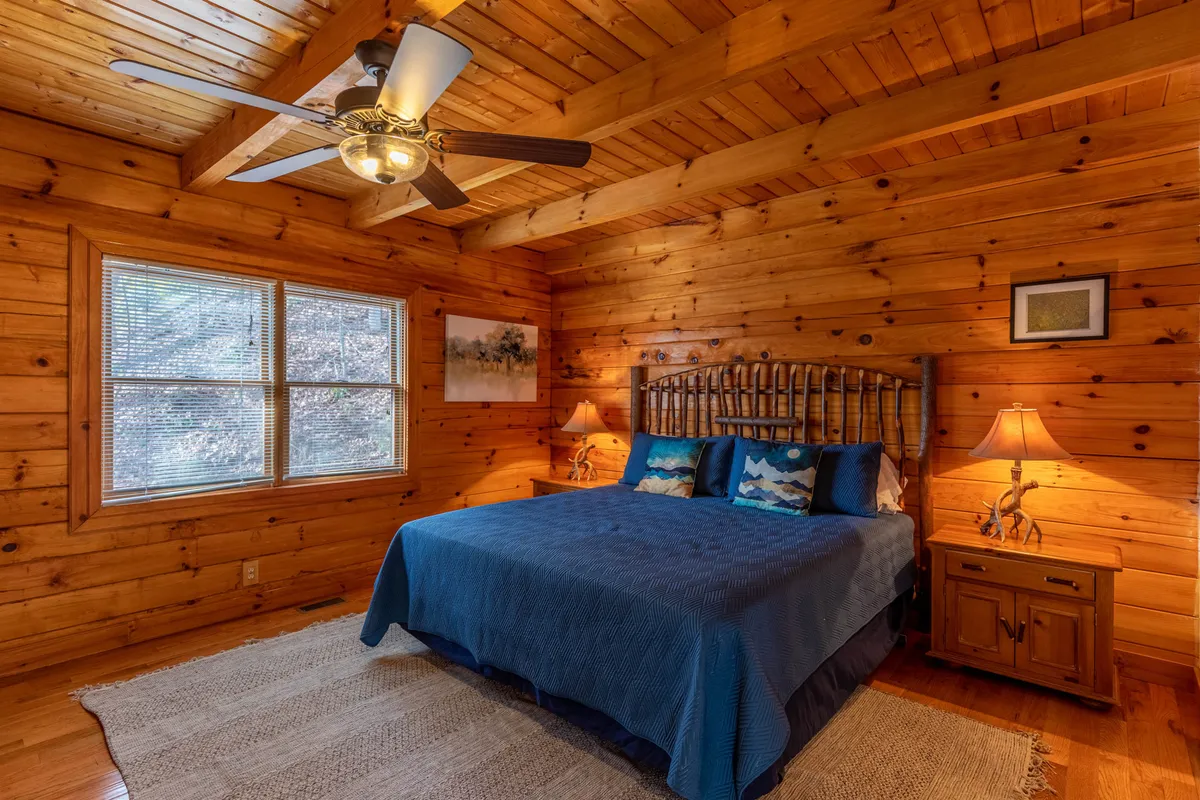 A serene bedroom with a plush bed, nightstands, and large windows that let in natural light and offer potential mountain views. The calming decor and peaceful atmosphere encourage moments of stillness and restorative rest.