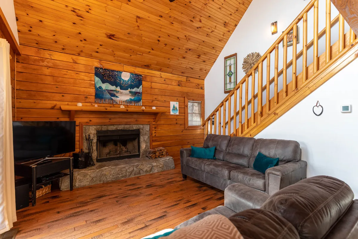 A cozy living area featuring a glowing wood-burning fireplace, a comfortable sofa positioned for intimate conversations, and tasteful artwork that adds to the serene ambiance. The inviting space is softly lit and encourages relaxation and connection.