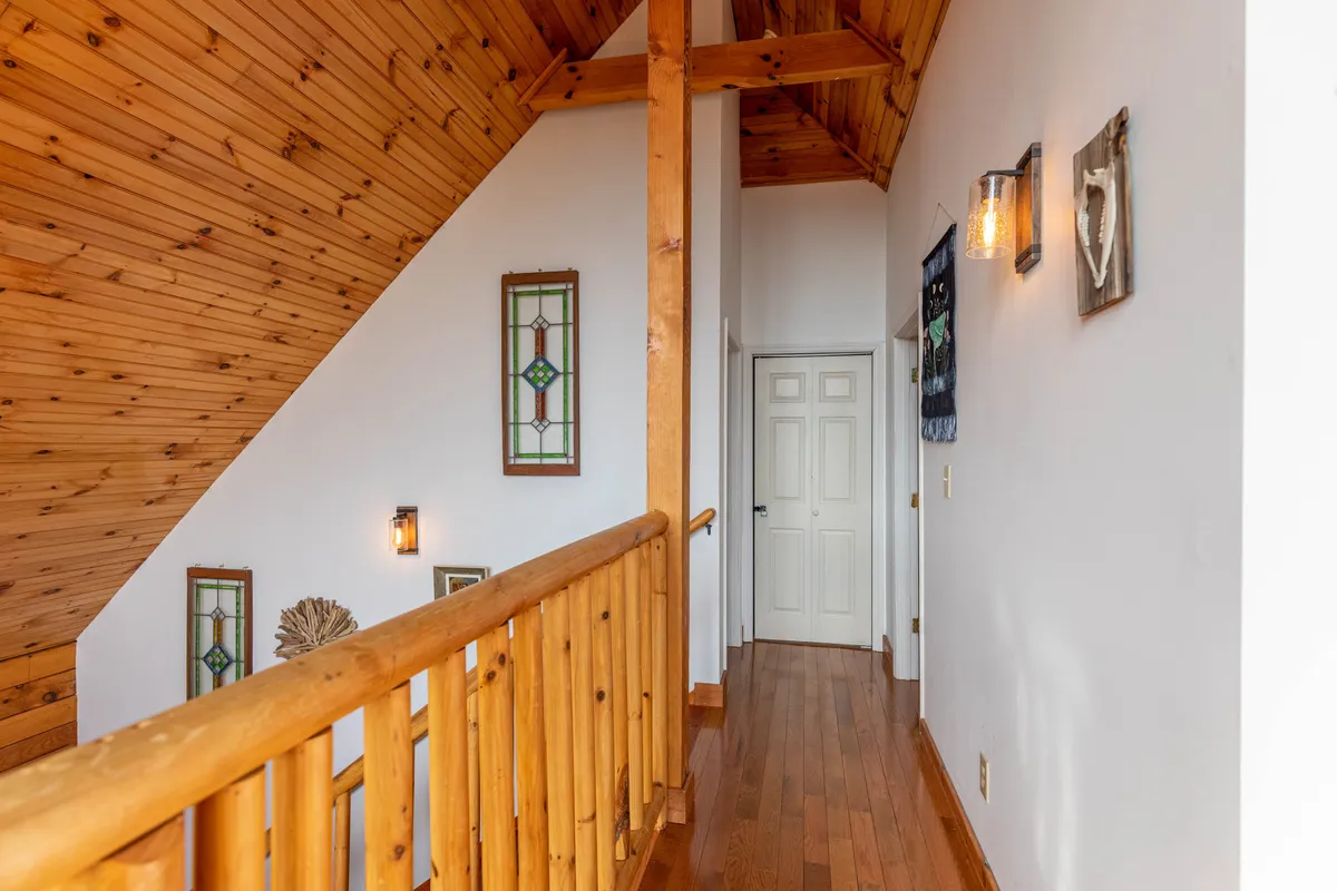 This image highlights the home's entryway, featuring a wooden railing, stained glass windows, and a view through a welcoming doorway. The decor and architectural details evoke a warm sense of arrival, while the glimpse of the outdoors through the windows offers a subtle connection to the surrounding mountain setting.